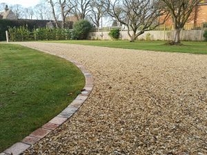 expansive gravel driveway with external lighting set with the block border