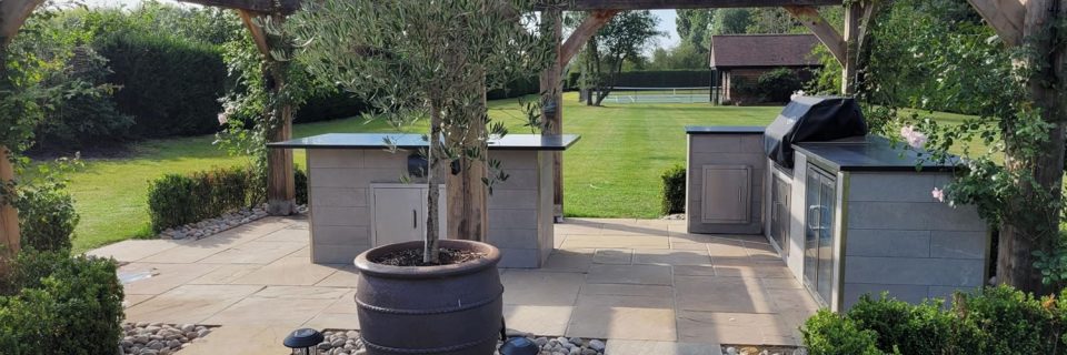 An Oak pergola with outdoor kitchen in a country house style paved setting